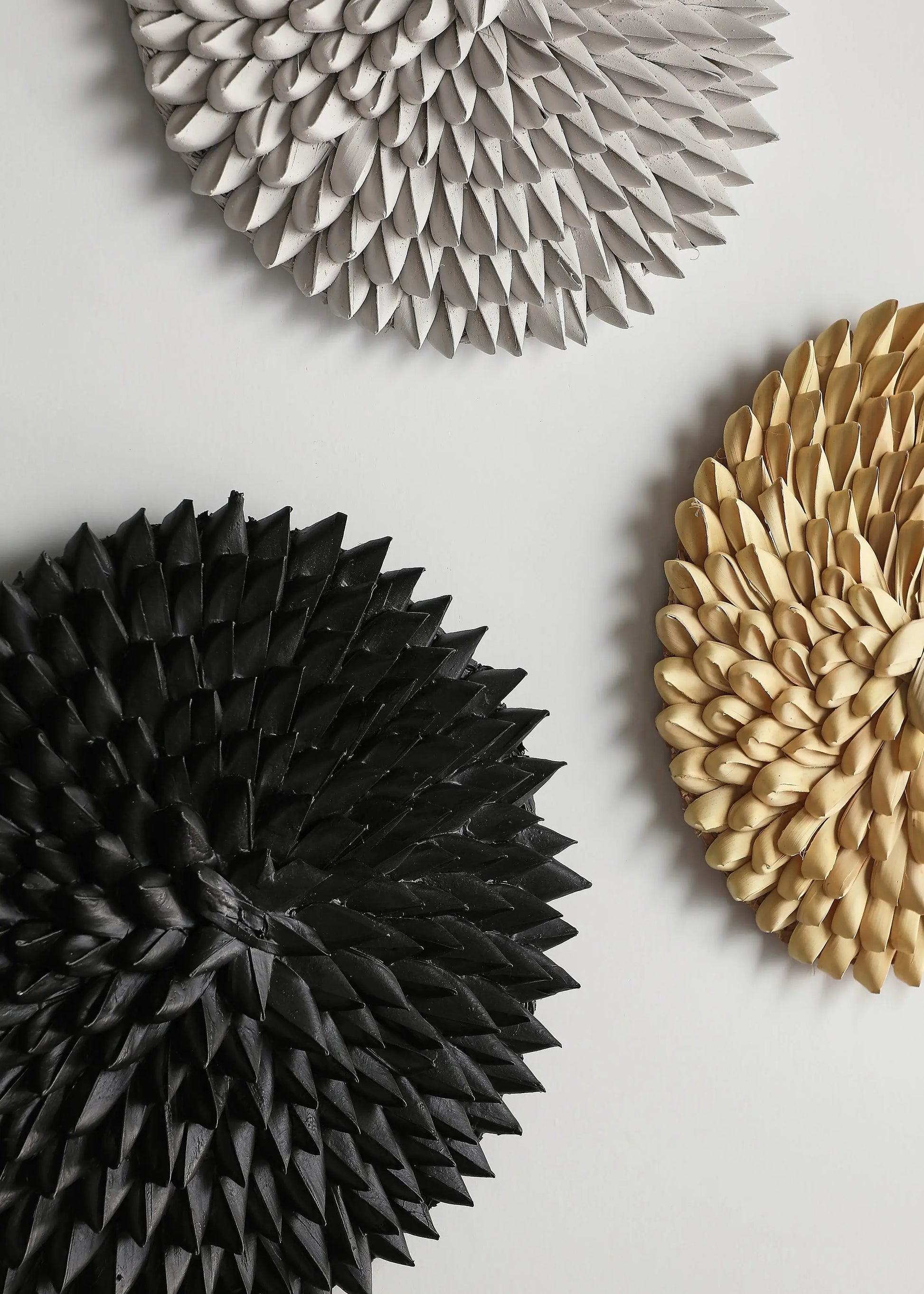 Three handmade porcupine wall baskets in black, gray, and beige on a light background