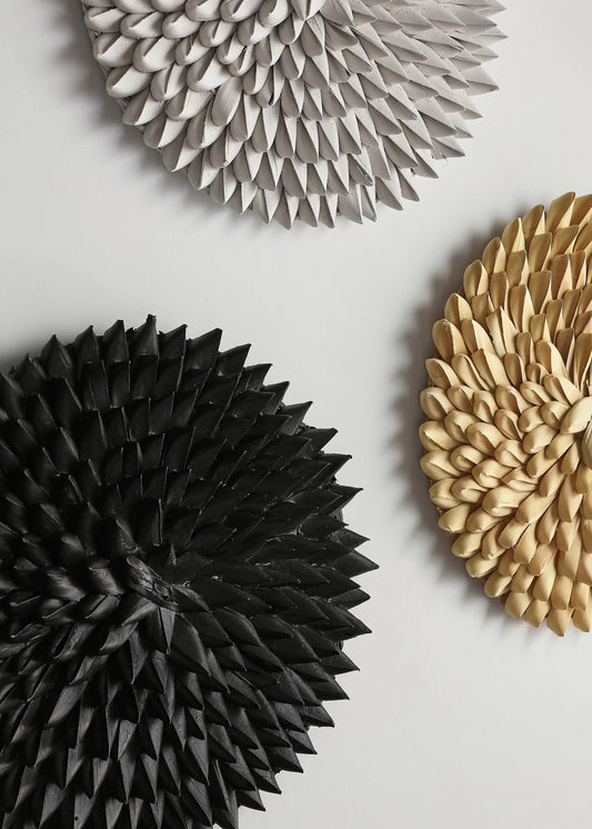 Three handmade porcupine wall baskets in black, gray, and beige on a light background