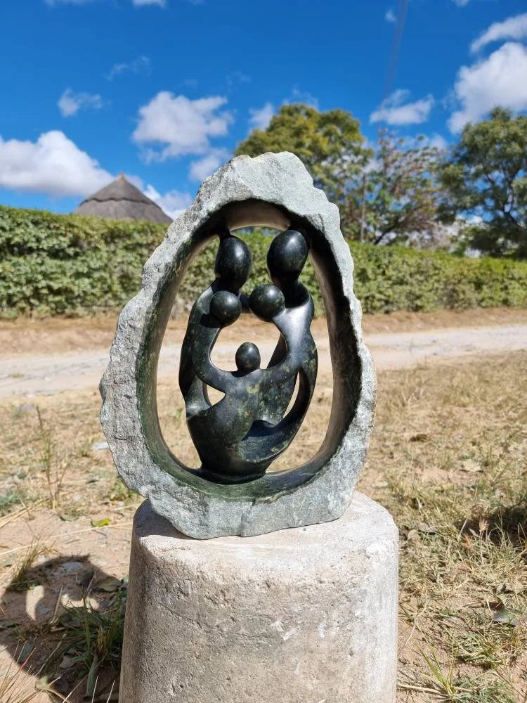 Abstract sculpture of a family on a stone pedestal with a scenic background